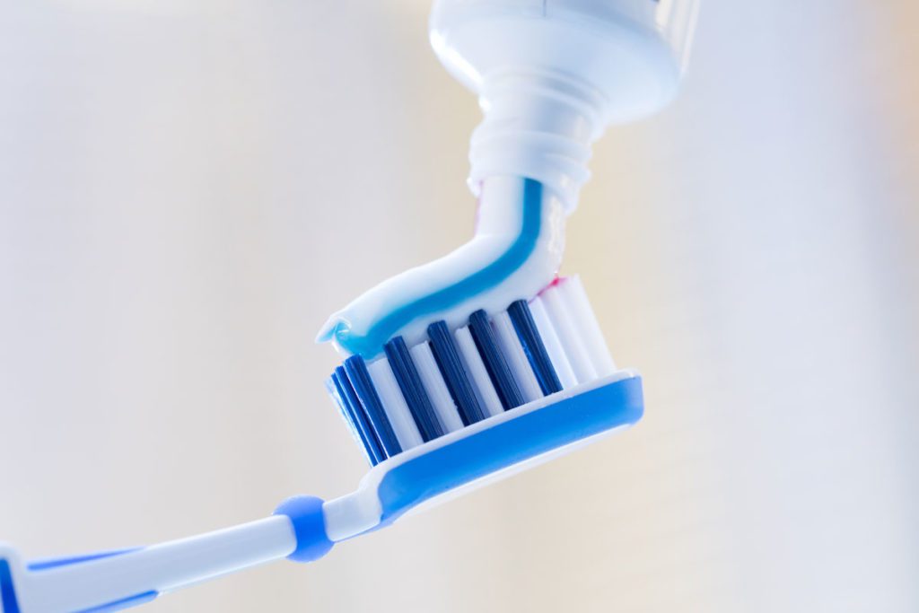 A patient at Tr City Dental uses fluoride toothpaste as part of their dental care routine.